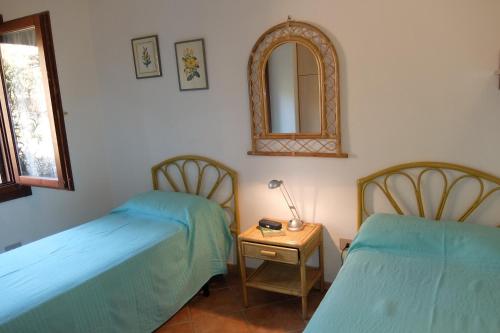 een kamer met 2 bedden en een tafel met een spiegel bij Villino Li Sambuli in Costa Paradiso