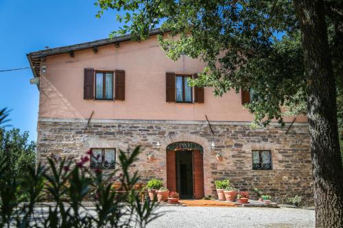 an old stone house with a tree in front of it at Agriturismo La Caputa in Urbania