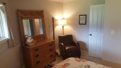 a bedroom with a dresser and a chair and a mirror at Deer Ridge B&B in Golden