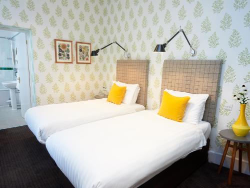 two beds in a room with yellow pillows at Embankment Hotel in Bedford