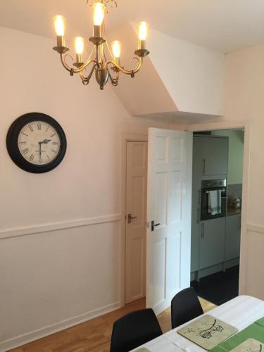 a dining room with a clock on the wall at Tynant House- Modern 3 bed house- City centre and FREE parking in Cardiff