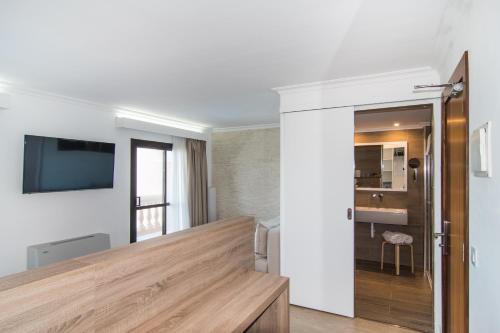 a living room with white walls and a wooden table at Hotel Na Taconera in Cala Ratjada