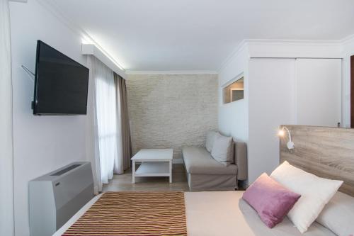 a bedroom with a bed and a tv and a couch at Hotel Na Taconera in Cala Ratjada