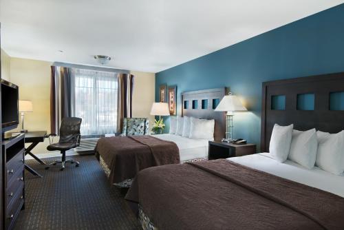 a hotel room with two beds and a desk at Oxford Suites Silverdale in Silverdale