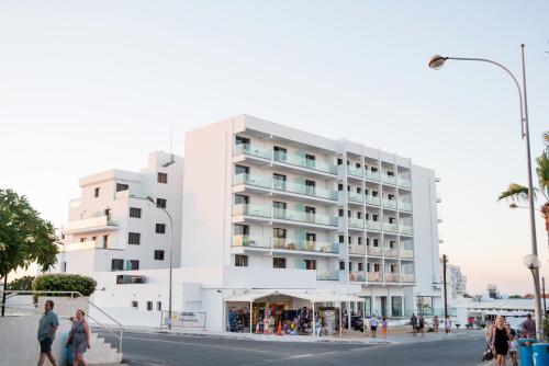 a white building with people walking in front of it at Mandali Hotel in Protaras