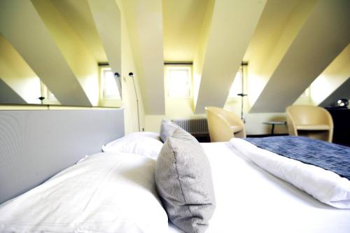 Schlafzimmer mit einem Bett mit weißer Bettwäsche und Kissen in der Unterkunft Hotel Ottheinrich in Weinheim