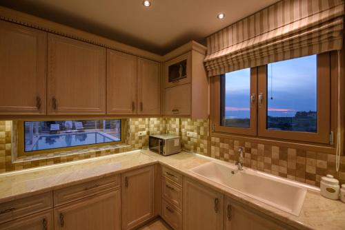 uma cozinha com um lavatório e duas janelas em Golden Sky Villa em Kamilári