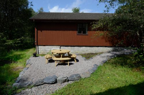 a picnic table and chairs in front of a building at Birchbrae Highland Lodges in Onich