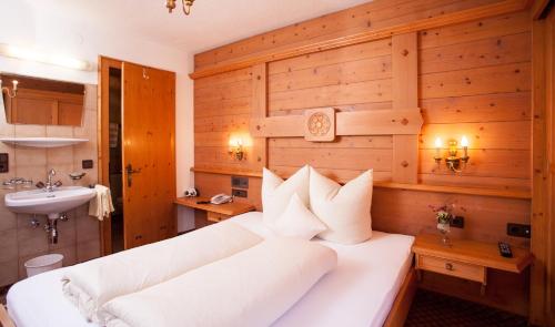 a bedroom with a large white bed and a sink at Vermunt 19a in Galtür