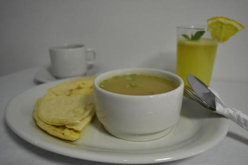 a white plate with a bowl of soup and a tortilla at Hotel El Principe Sede Campestre in Ocaña