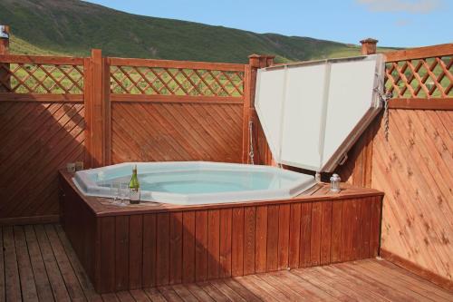 a hot tub on a deck with a wooden fence at Geysir - Modern Log Cabin in Reykholt
