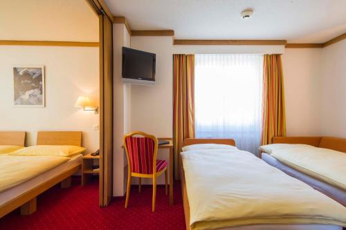 a hotel room with two beds and a tv at Hotel Excelsior in Zermatt