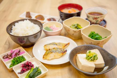 京都市にある相鉄フレッサイン 京都四条烏丸の食べ物の皿とご飯の入ったボウルが置かれたテーブル