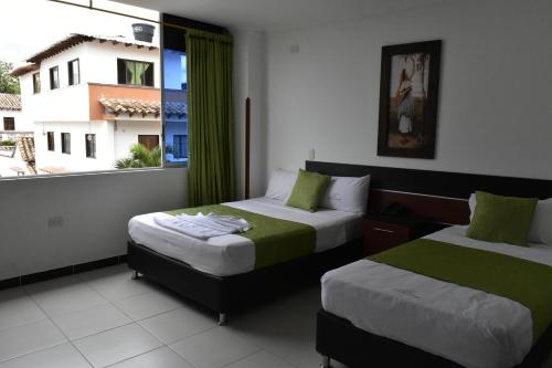 a hotel room with two beds and a window at Hotel El Principe Sede Campestre in Ocaña