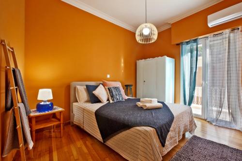 Schlafzimmer mit orangefarbenen Wänden, einem Bett und einem Fenster in der Unterkunft Athens Centre Apartment in Athen