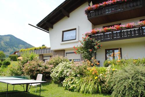 a building with a table and flowers in front of it at Ferienwohnung Gästehaus Inge in Zlan