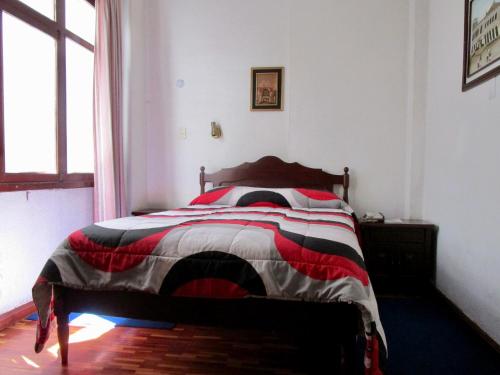 a bedroom with a bed with a red white and black comforter at Hotel Huasi Continental in Quito