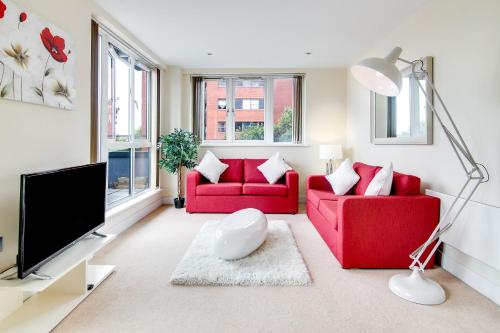 a living room with two red couches and a flat screen tv at The Class Place in Birmingham