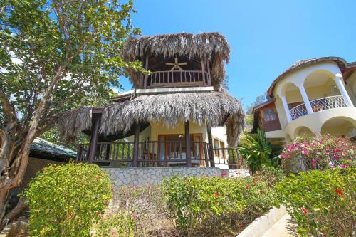 a house with a thatch roof on top of it at Catcha Falling Star in Negril