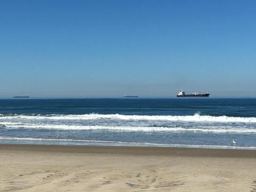 a beach with waves and a tanker in the ocean at Hotel Mares do Sul in Tramandaí