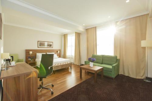 マハチカラにあるHotel Jacquesのベッドと緑の椅子が備わるホテルルームです。