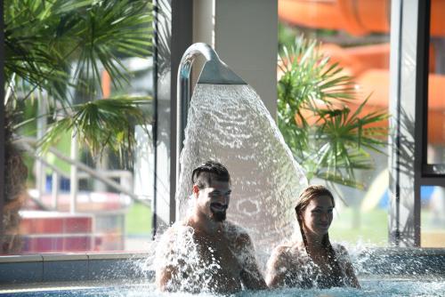 a man and a woman in a swimming pool at Sport Hotel in Tatabánya