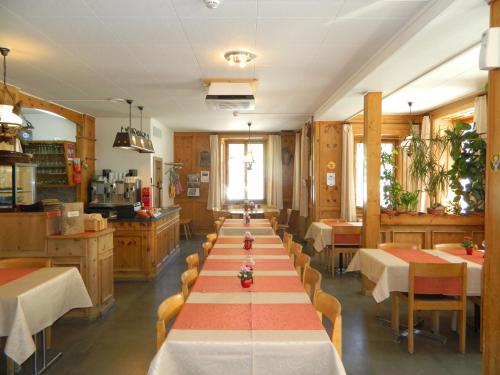Hotel Preda Kulm في بيرغون: طاولة طويلة في مطعم مع طاولات وكراسي