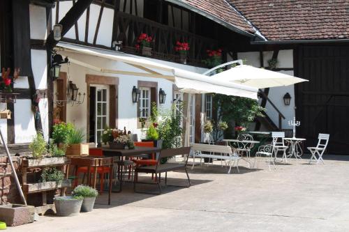 d'une terrasse avec des tables, des chaises et un parasol. dans l'établissement La Grange aux Coqs, à Ittenheim
