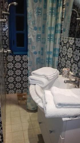 a bathroom with a sink and a shower with towels at Dar El Kasba Riad Guest House in Bizerte