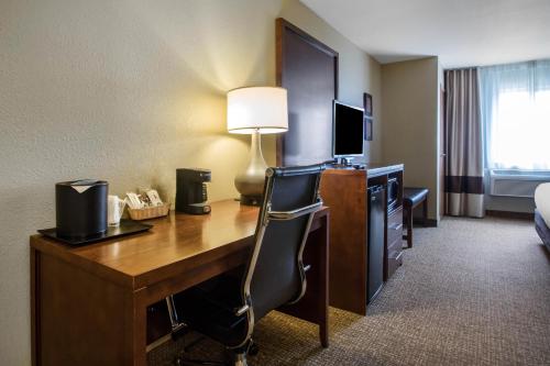 a hotel room with a desk with a lamp and a bed at Comfort Suites Johnson Creek Conference Center in Johnson Creek