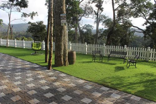 a park with two benches and a white fence at 31st December Farms And Estates Munnar in Munnar