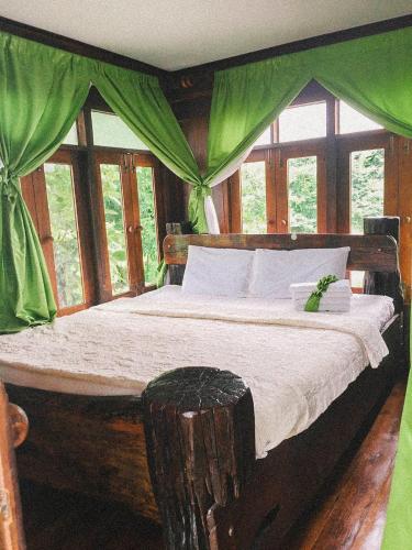 a bedroom with a wooden bed with green curtains at Sukhothai City Resort in Sukhothai
