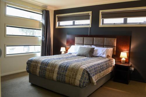 a bedroom with a bed with two lamps and two windows at Atricom in Stanthorpe