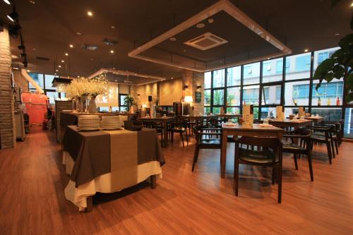 a dining room with tables and chairs and windows at Vella Suite Hotel in Suwon