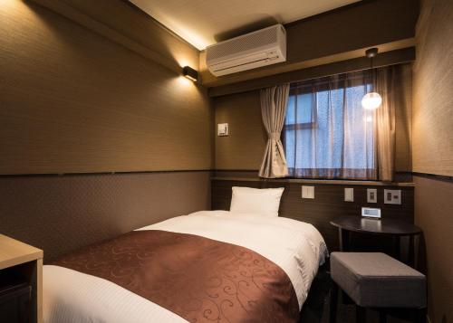 a small room with a bed and a window at Hotel SUI Ginza Kyobashi by ABEST in Tokyo