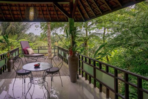 a porch with chairs and a table on a balcony at Alassari Plantation in Selemadeg