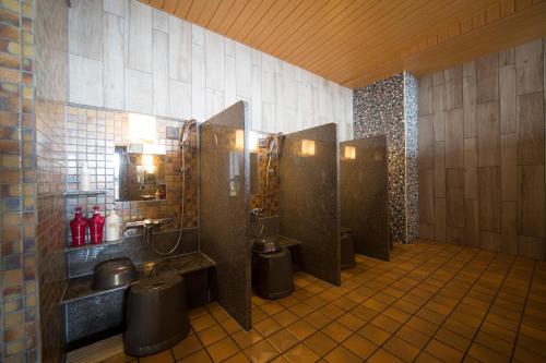 a bathroom with three stalls with toilets and sinks at Dormy Inn Izumo in Izumo