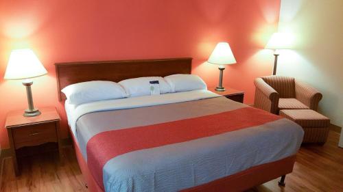 een slaapkamer met een bed met 2 lampen en een stoel bij Motel 6-Maryland Heights, MO in Maryland Heights