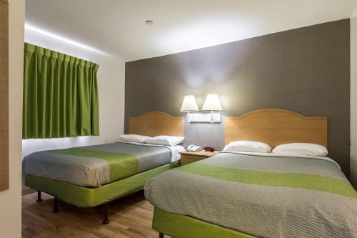two beds in a hotel room with green curtains at Studio 6-Lafayette, LA - Broussard in Lafayette