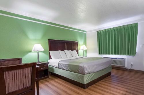 a hotel room with a bed and green walls at Motel 6-Kingsburg, CA in Kingsburg