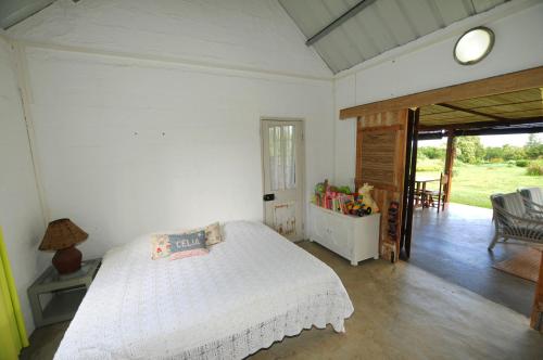 een slaapkamer met een wit bed en een glazen schuifdeur bij The Kiter’s Nest Baie du Cap in Choisy