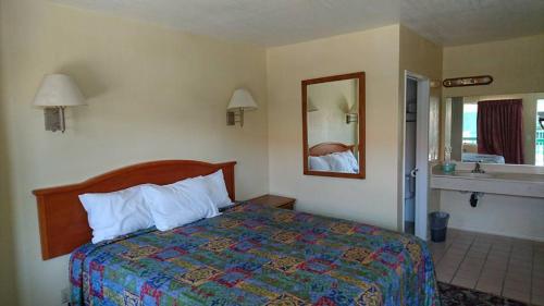 Habitación de hotel con cama y espejo en Bristol Motel en Long Beach