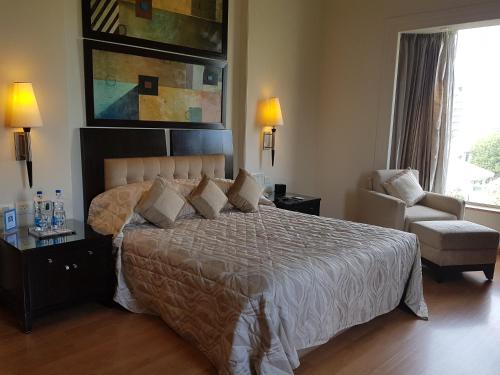 a bedroom with a bed and a chair and a window at Park Plaza Gurgaon in Gurgaon