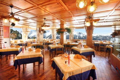 ヴァルディソットにあるChalet Dei Rododendriの山を背景にテーブルと椅子が備わるレストラン