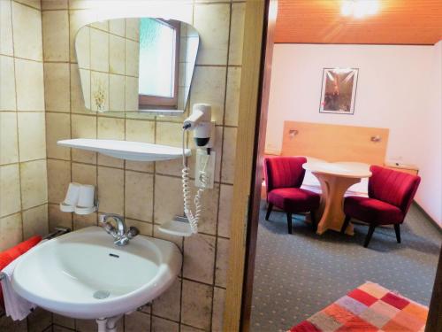 a bathroom with a sink and a table with red chairs at Haus Astrid-Christoph in Finkenberg