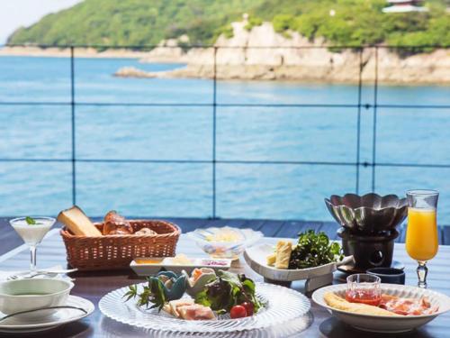 a table with food and a view of the ocean at Migiwatei Ochi Kochi in Fukuyama