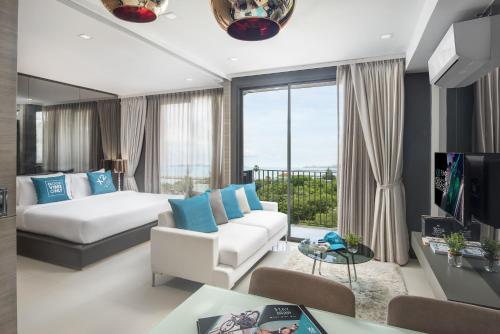 Habitación de hotel con cama y sala de estar. en Cross Vibe Pattaya Seaphere - formerly X2 Vibe Pattaya Seaphere, en Na Jomtien