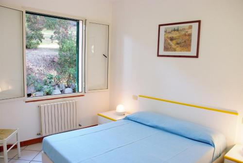 a bedroom with a blue bed and a window at Residence della Luna in Porto Azzurro