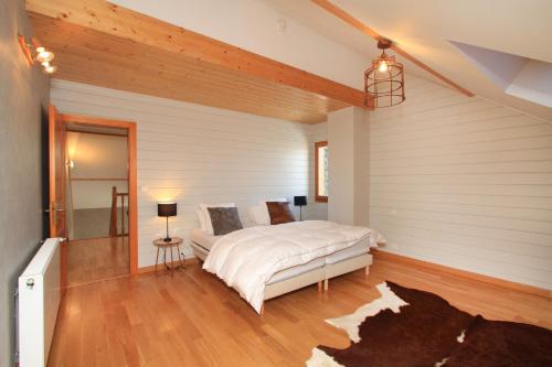 a bedroom with a bed in a room with wood floors at Chalet la roche du rain in Gérardmer