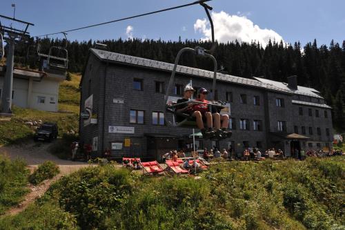 two people sitting on a ski lift in front of a building at Gasthof Kirchenwirt in Lackenhof